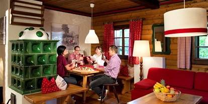 Mountainbike Urlaub - Hotel-Schwerpunkt: Mountainbike & Familie - Obertauern - Wohnraum Ausstattung Gipfel mit Essecke und Kachelofen  - Slow Travel Resort Kirchleitn