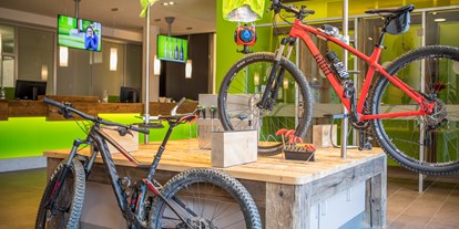 Mountainbike Urlaub - Bikeverleih beim Hotel: Zubehör - Bike Area mit Werkbank, Sportlockern, Tourenvorschlägen an der Explorer Wall und Verleih von E-Mountainbikes. - Explorer Hotel Kitzbühel