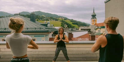 Mountainbike Urlaub - PLZ 8982 (Österreich) - Yoga im Freien auf der Terrasse mit Blick über die Dächer von Schladming - Stadthotel Brunner