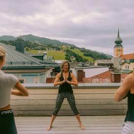 Mountainbikehotel: Yoga im Freien auf der Terrasse mit Blick über die Dächer von Schladming - Stadthotel Brunner
