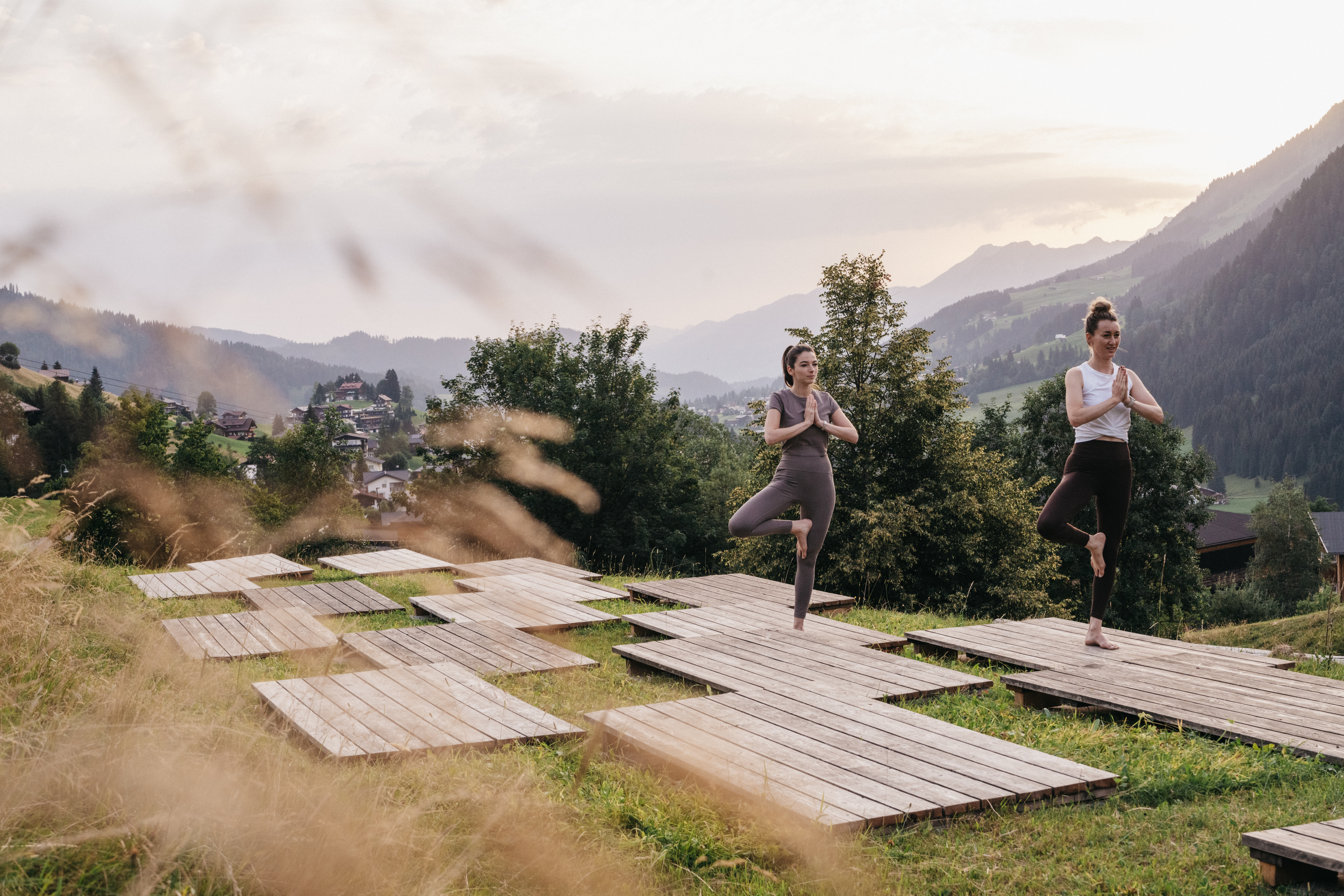 Mountainbike Urlaub - Arzl im Pitztal - Zwei Frauen auf Yogaplattform am frühen Morgen - Das Naturhotel Chesa Valisa****s